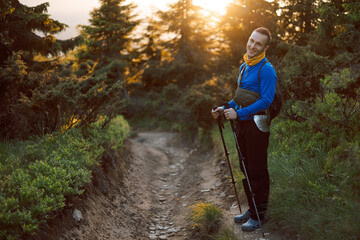 portrait of a hiker with trekking poles and backpack climbing or descending mountain hiking trails