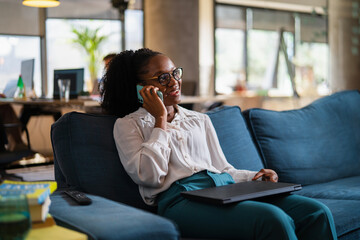 Black businesswoman working on laptop. Portrait of beautiful businesswoman talking to the phone in...