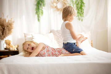 Cute sweet toddler children, tickling feet on the bed, laughing and smiling