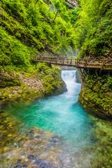 A long exposure view down the turbulent Radovna River past a walkway in the Vintgar Gorge in Slovenia in summertime
