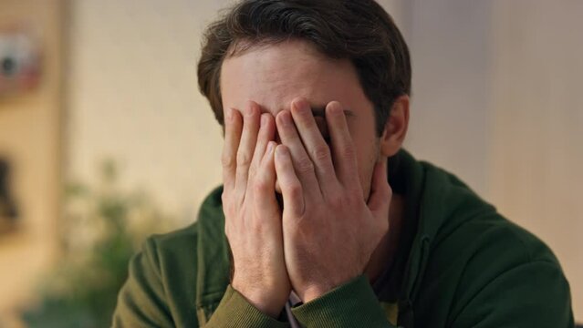 Disappointed man covering face palm in office closeup. Tired creator worried