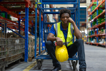 African American man worker stressed and overworked in warehouse factory. Storehouse employee in...