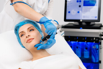 Fototapeta premium Facial treatment. Nice young woman lying on the medical bed while having a beauty procedure