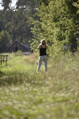 girl photographer photographing nature, walking in the woods, back view. young woman in spring forest. girl tourist. enjoying spring weather. Rest, lifestyle, walk in the fresh air. hiking in nature