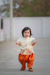 A cute girl kid is wearing in traditional Thai dress, holding a silver water dipper in Songkarn festival, the most famous water playing in Thailand.