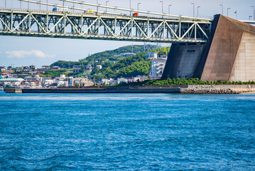 Fototapeta premium フェリーの上から見た明石海峡大橋の橋脚部分（淡路島側）と漁港町である岩屋の風景