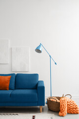 Interior of light living room with blue sofa and lamp
