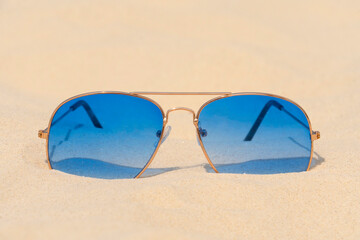 Blue sunglasses lie on the sand. Summer vacation, travel and tourism concept