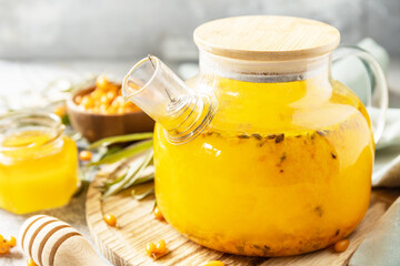 Healthy sea ​​​​buckthorn tea with honey on a gray stone background. Autumn tea, berries seasonal drink.