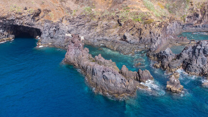Obraz premium Aerial view of rocky cliffs on the coast of Madeira at the Atlantic ocean with clear blue water
