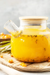 Healthy sea ​​​​buckthorn tea with honey on a gray stone background. Autumn tea, berries seasonal drink. Copy space.