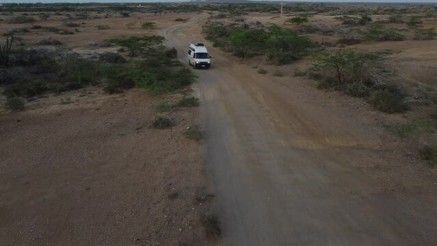 Road trip through the desert small white van on a gravel road in The Guajira Desert Colombia Aerial Video