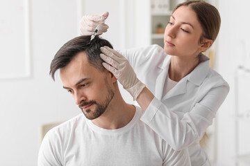 Handsome man receiving injection for hair growth in clinic
