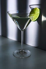 Glass of martini with lime on blue background