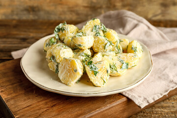 Plate of tasty Potato Salad with greens on wooden background
