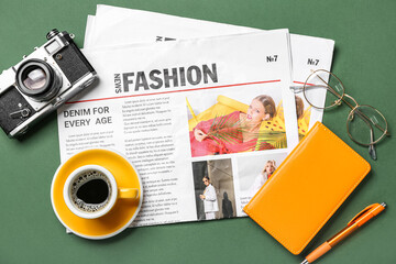 Newspapers with cup of coffee, photo camera, eyeglasses and notebook on green background