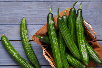 Basket with fresh cucumbers on grey wooden background, closeup