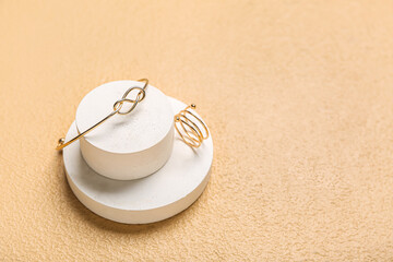 Showcase pedestals with golden ring and bracelet on beige background