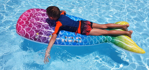 
The child floats on an inflatable mattress in the pool. Summer vacation for a family with children...