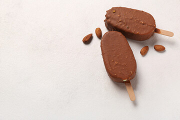 Delicious chocolate covered ice cream and almond nuts on white table