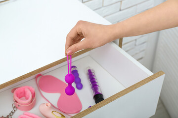 Woman taking anal plug from drawer at home, closeup