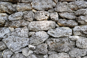 Texture of stone wall made of naturally perforated rocks covered with moss as a background