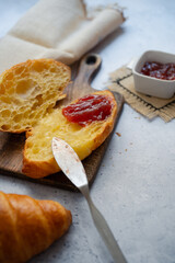 Desayuno dulce de croissant abierto untando mermelada