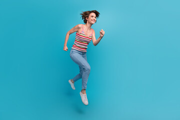 Full size profile photo of pretty cheerful girl jumping hurry run empty space isolated on blue color background