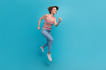 Full size profile photo of pretty cheerful girl jumping hurry run empty space isolated on blue...