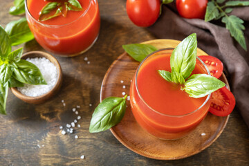 Vegetable tomato drink for a healthy diet. Glasses of fresh tomato juice  with tomatoes, salt on wooden table.