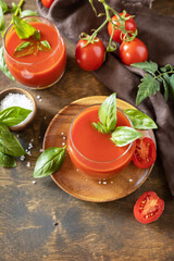 Vegetable tomato drink for a healthy diet. Glasses of fresh tomato juice  with tomatoes, salt on wooden table. Copy space.