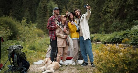 A group of happy tourists in special hiking clothes take a selfie against the backdrop of a green forest. Active lifestyle, walking and hiking. Selfie as a memory of the event