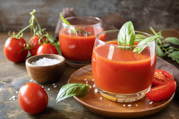 Glasses of fresh tomato juice  with tomatoes, salt on wooden table. Vegetable tomato drink for a healthy diet.