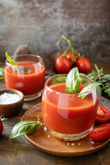 Vegetable tomato drink for a healthy diet. Glasses of fresh tomato juice  with tomatoes, salt on wooden table. Copy space.
