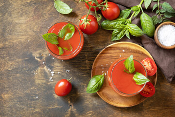 Glasses of fresh tomato juice  with tomatoes, salt on wooden table. Vegetable tomato drink for a healthy diet. View from above. Copy space.