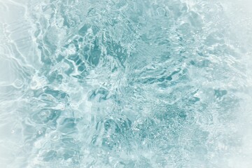 Blue water with ripples on the surface. Defocus blurred transparent blue colored clear calm water surface texture with splashes and bubbles. Water waves with shining pattern texture background.