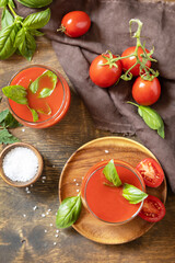 Glasses of fresh tomato juice  with tomatoes, salt on wooden table. Vegetable tomato drink for a healthy diet. View from above.