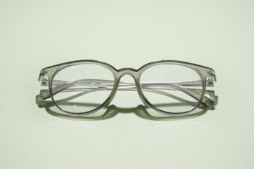 Stylish grey eyeglasses on pale green background