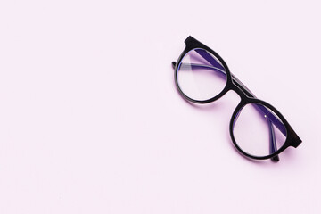 Stylish black eyeglasses on lilac background