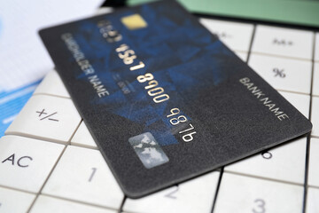 Credit card with calculator and business infographics on table