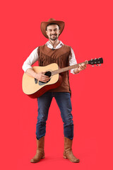 Handsome cowboy playing guitar on red background