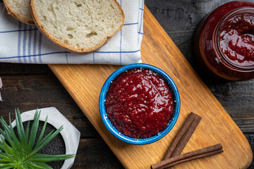 Fresh homemade raspberry jam in a bowl served on a wooden platter with bread