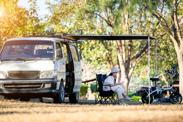 Asian woman travel and camping alone by camper van at park in Thailand. Recreation and journey outdoor activity lifestyle.