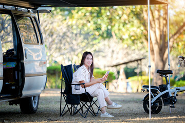 Asian woman travel and camping alone by camper van at park in Thailand. Recreation and journey outdoor activity lifestyle.
