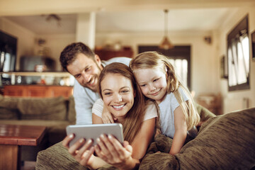 Fototapeta premium Young family taking a selfie on the couch in the living room