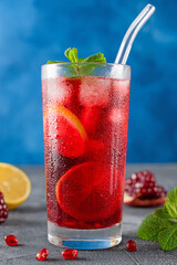 Iced red lemonade drink with fresh mint, sugar syrup and pomegranate juice in glass on a dark...