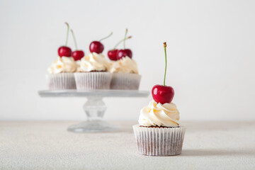 Tasty cherry cupcake on light background