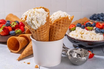 Cottage cheese ice cream, trendy white cottage cheese vanilla ice cream scoops in waffle cones, with fresh berries and toppings 