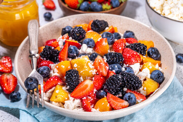 Summer fruit and berry salad with cottage cheese. Big bowl with breakfast or lunch salad with sliced fruits, blueberry, strawberry, blackberry and high-protein curd cheese sauce