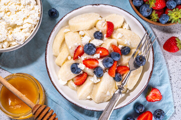 Homemade cottage cheese boiled gnocchi with berries, lazy dumplings vareniki with fresh strawberry and blueberry 